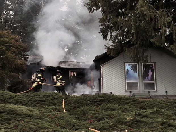 Kent firefighters work to douse a house fire in the 25100 block of 142 Avenue Southeast on Sunday morning. All six occupants were able to get out safely.