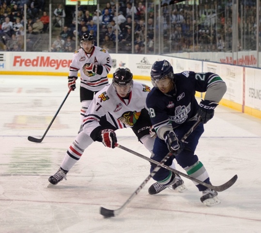 The Thunderbirds' Keegan Kolesar brings the puck up the ice with the Winterhawks' Paul Bittner defending.