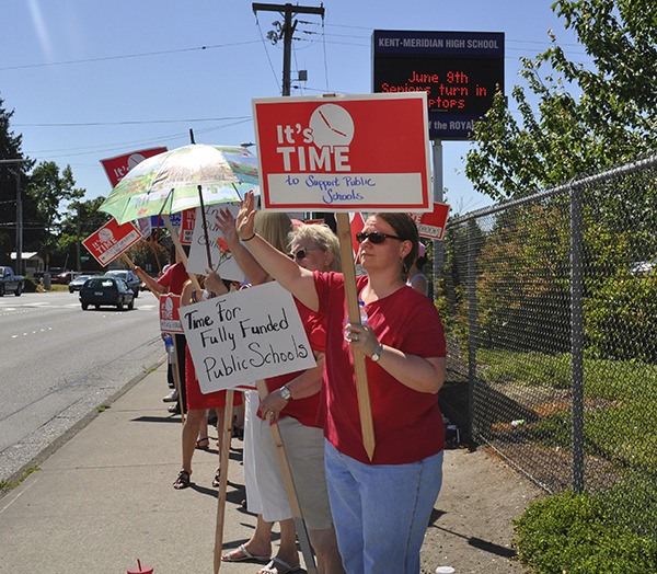 Teachers wave signs in front of Kent-Meridian High School on Monday afternoon.