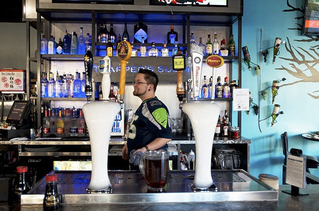 Bartender Chris Watson wears a Richard Sherman jersey during his  Blue Friday shift at Trapper’s Sushi at the Kent Station shopping mall.