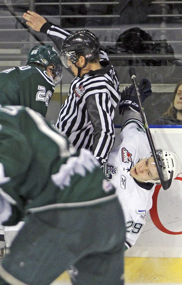 The Silvertips' Cole MacDonald and an official jar the T-Birds' Roberts Lipsbergs along the boards.