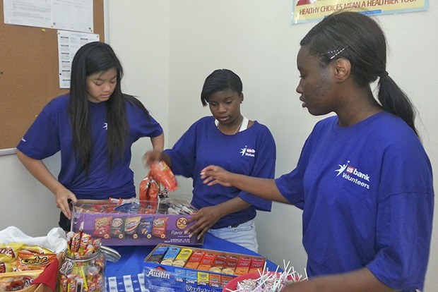 U.S. Bank employee volunteers prepare snacks at the backpack and school supplies event at Mercy Housing’s Appian Way Apartments last week.