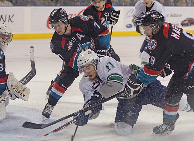 Kelonwa defensemen Damon Severson (7) and Colten Martin (8) battle the Thunderbirds' Branden Troock in front of the Rockets' goal.