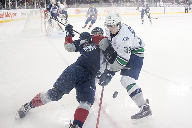 The Thunderbirds' Nick Holowko tangles with an American in a battle for the puck during action Tuesday night at the ShoWare Center.