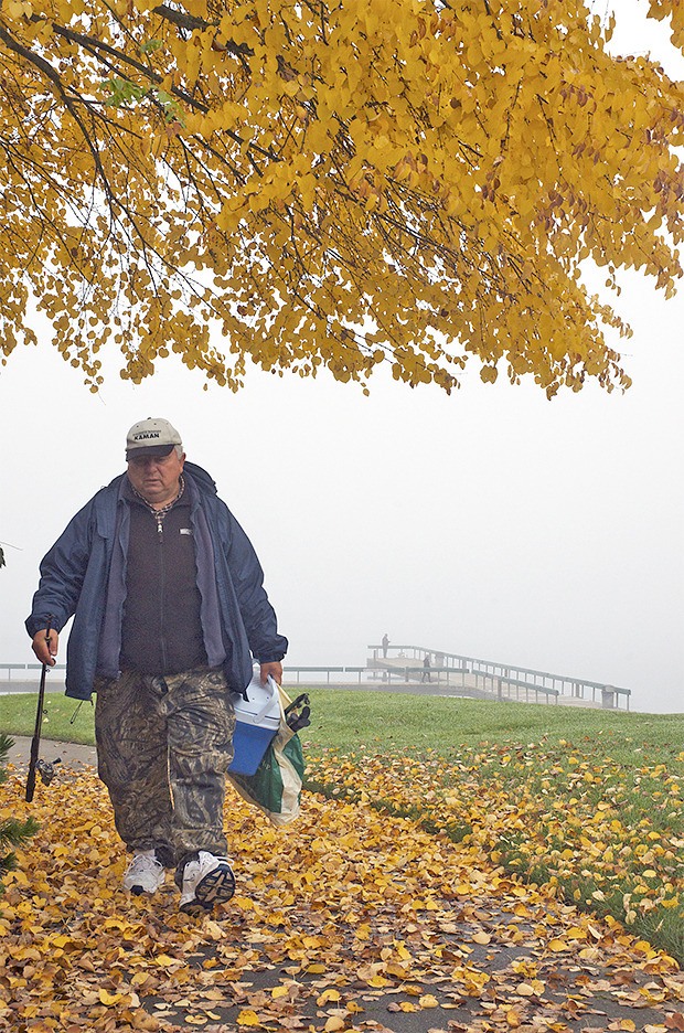 A fisherman returns from a fruitless attempt as fog shrouded the Lake Meridian fishing pier Tuesday morning.