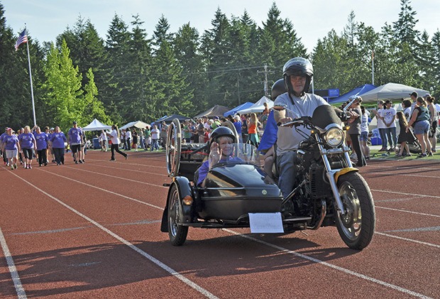 Marlene Helmbrecht rides in the sidecar of a motorcycle during the opening lap of Kent's Relay of Life last Friday night at French Field. Helmbrecht