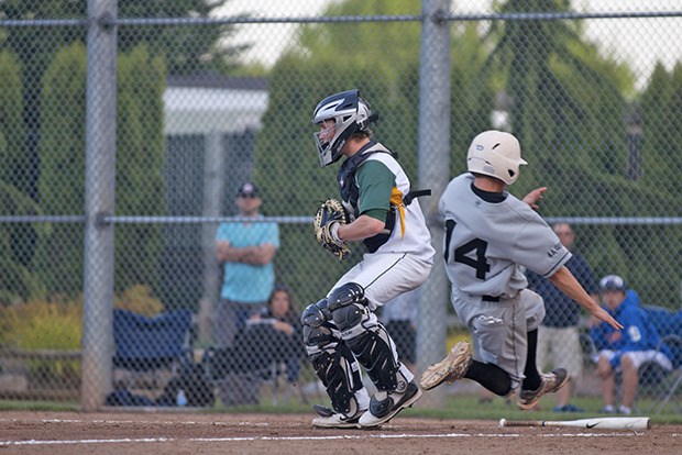 Kentridge catcher Shane Stober waits for a throw as a Battle Ground player slides home safely.