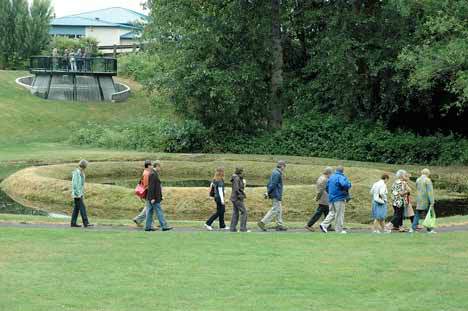 A tour group strolls past an earthen structure in June 2009 at Kent's Mill Creek Canyon Earthworks Park. The tours were organized by the national group Americans for the Arts