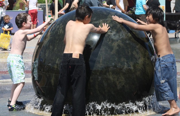 Kids enjoy the Rotary granite ball that floats on water on a sunny and warm Saturday