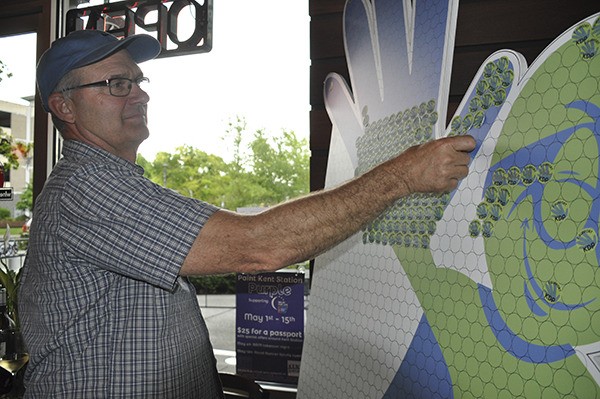 Merle Reeder places a sticker on High 5 Guy – mascot for the Kent Downtown Partnership’s High 5 fundraising campaign – during a kickoff event at Reds Wine Bar at Kent Station on April 28.