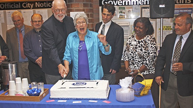 Kent Mayor Suzette Cooke and former mayor Jim White prepare to cut the city’s 125th anniversary cake during a reception on Tuesday night at City Hall. Looking on