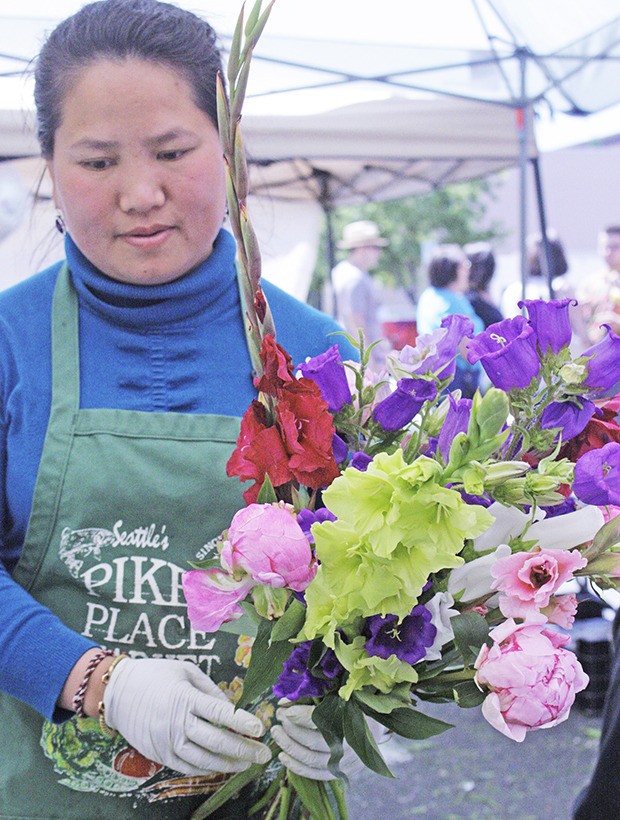 Kia Xiong prepares freshly cut flowers for sale during the Kent Farmers Market last Saturday.