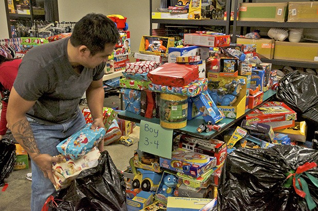 Chester Patoc adds pre-wrapped presents to the toy dispensary tables during the Toys for Joy program at the Kent Food Bank on Friday. About 75 volunteers gathered to help collect