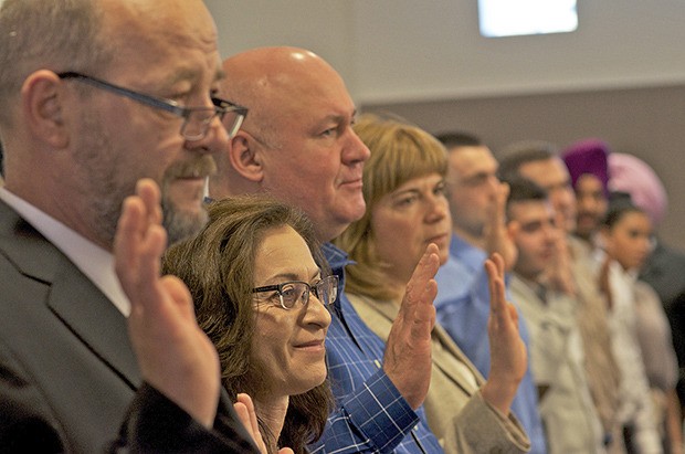 Immigrants from as close as Canada and as far as India raise their right hands to take the Oath of Allegiance to the United States.