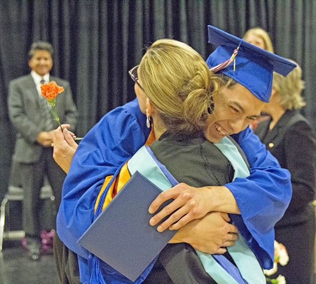 Kent Phoenix Academy Principal Merrilee Lyle hugs  2013 graduate Brennon Potts at commencement.