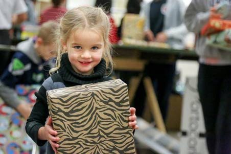 An unidentified girl helps out last Friday at a Toys for Joy gift wrapping party run by Kent firefighters. Volunteers will distribute toys this week.