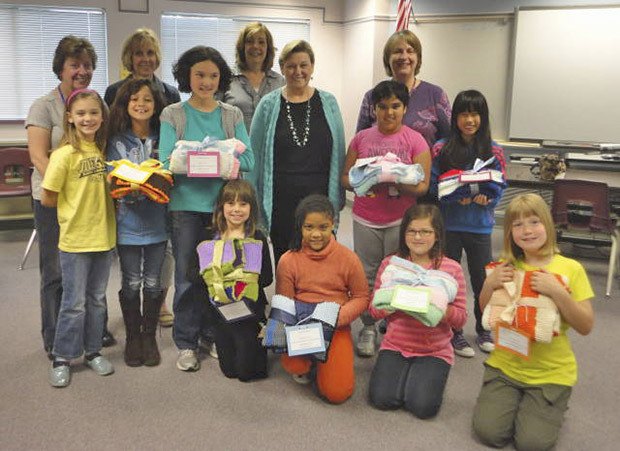 Sunrise Elementary students display carseat blankets they knitted for the Pediatric Care Center in Kent. From back row from left: staff members Sharon Orlowski