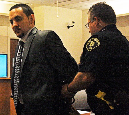 A King County corrections officer handcuffs Leland D. Russell Jr. after opening statements during his trial on Monday in Kent for two murders at a Shell station in August 2014.