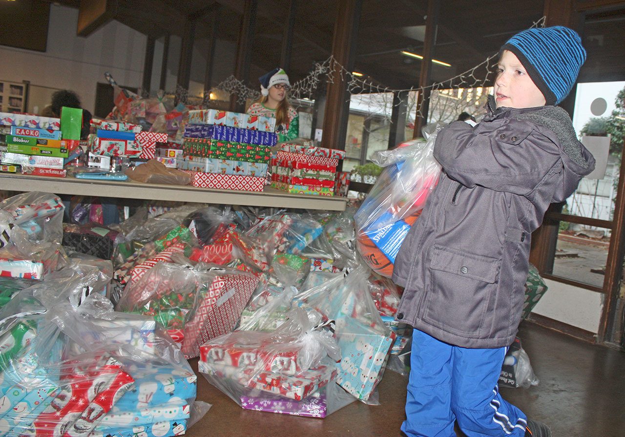 A boy helps carry a bag of donated toys inside Kent Lutheran Church for distribution. MARK KLAAS, Kent Reporter