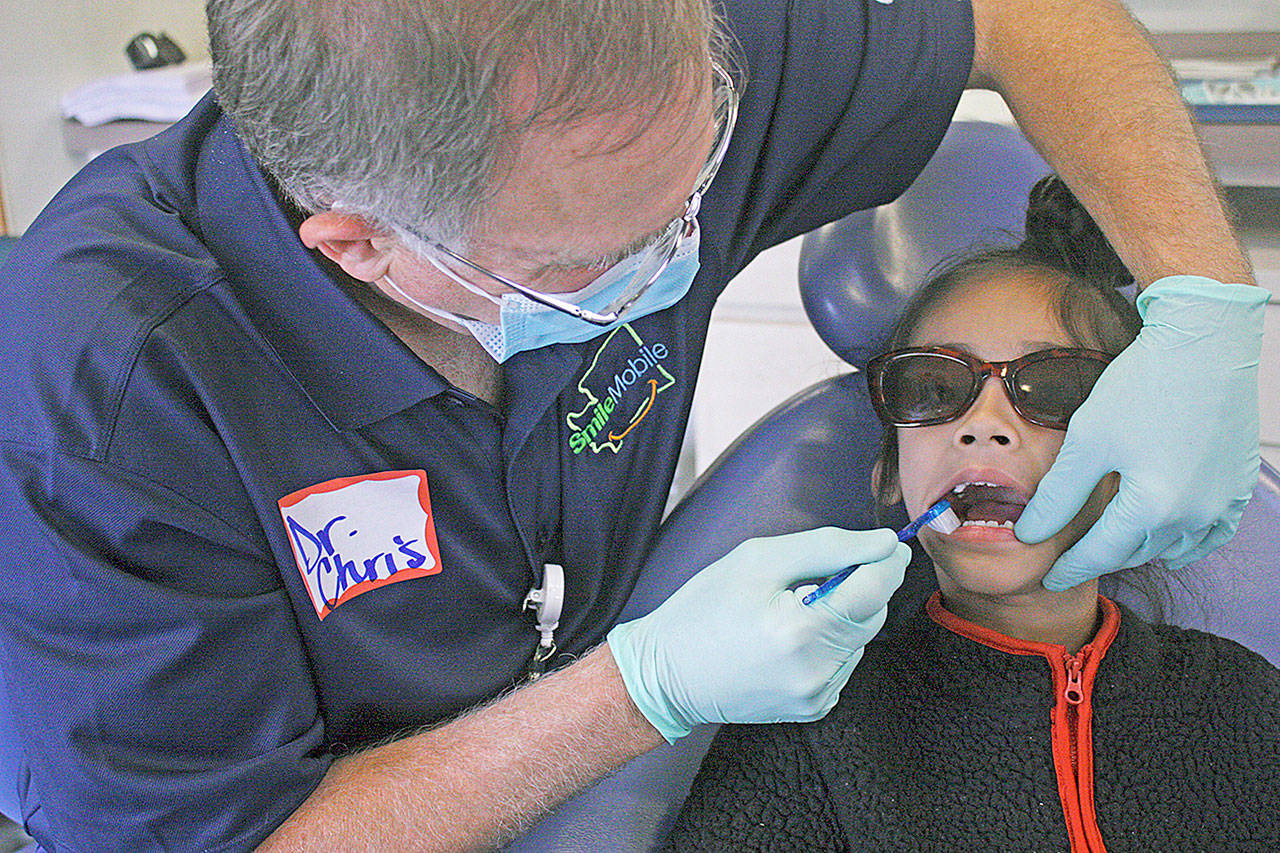 Dr. Chris Delecki examines Sohang Nannar during the SmileMobile’s visit to Kent Elementary School on Monday. MARK KLAAS, Kent Reporter