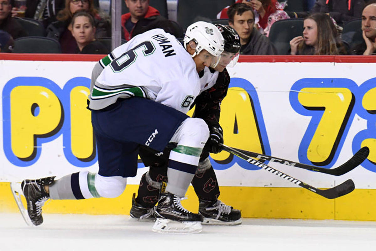 The Thunderbirds’ Aaron Hyman battles a Calgary player along the boards during WHL play Saturday. COURTESY PHOTO, Candice Ward