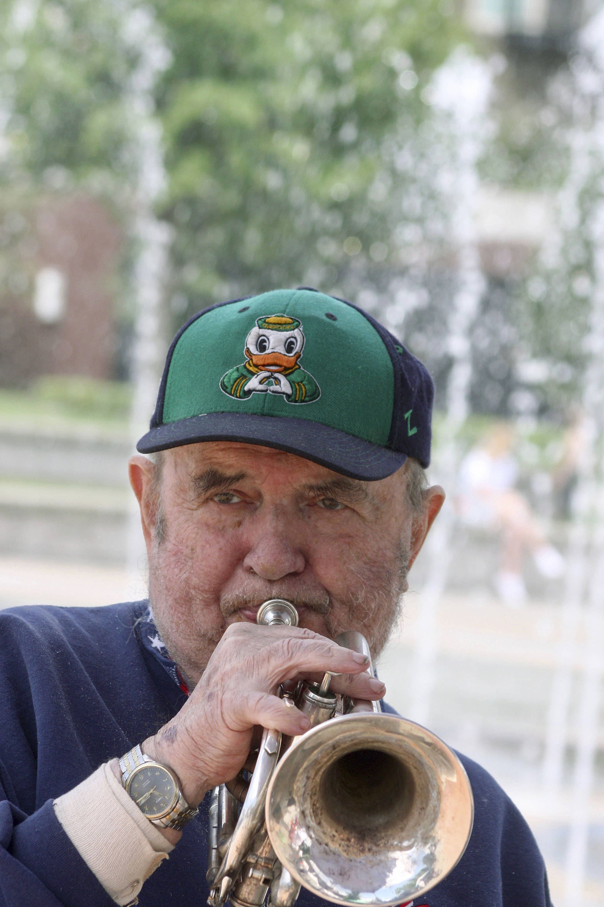 Bert Barr blows his trumpet as he entertains passers-by during the opening of the Kent Farmers Market at the Town Square Plaza last Saturday. Bert plays trumpet and percussion and his wife, Rose Marie, plays piano. Together, the Double Barrs perform jazz and swing music from yesteryear. MARK KLAAS, Kent Reporter