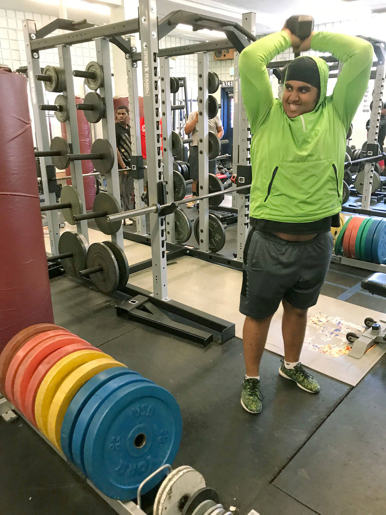 Sophomore Sam Singh does some tricep extensions as donated bumper plates glow on the racks in the Kent-Meridian High School weight room on Monday. MARK KLAAS, Kent Reporter