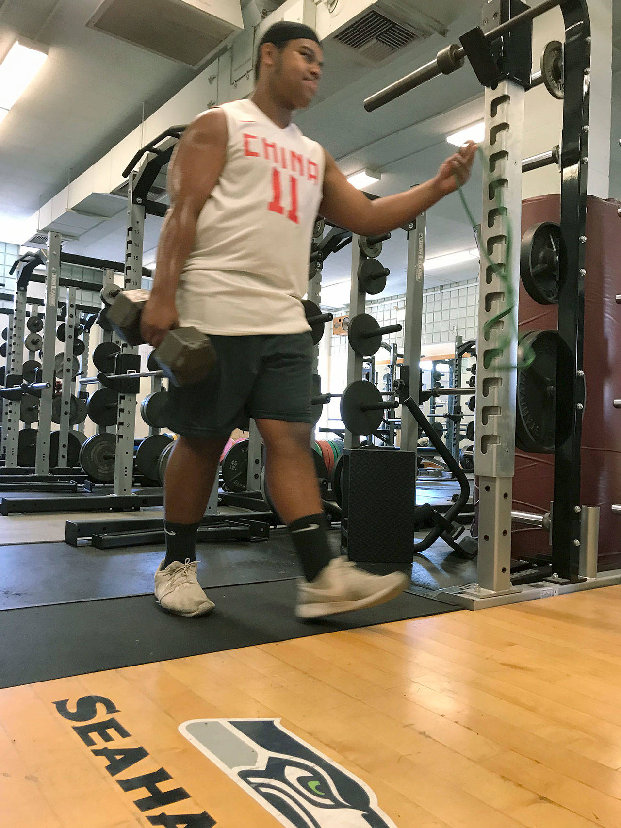 Freshman Etu Tuifua carries a barbell in front of a donated power rack in the Kent-Meridian High School weight room on Monday. MARK KLAAS, Kent Reporter