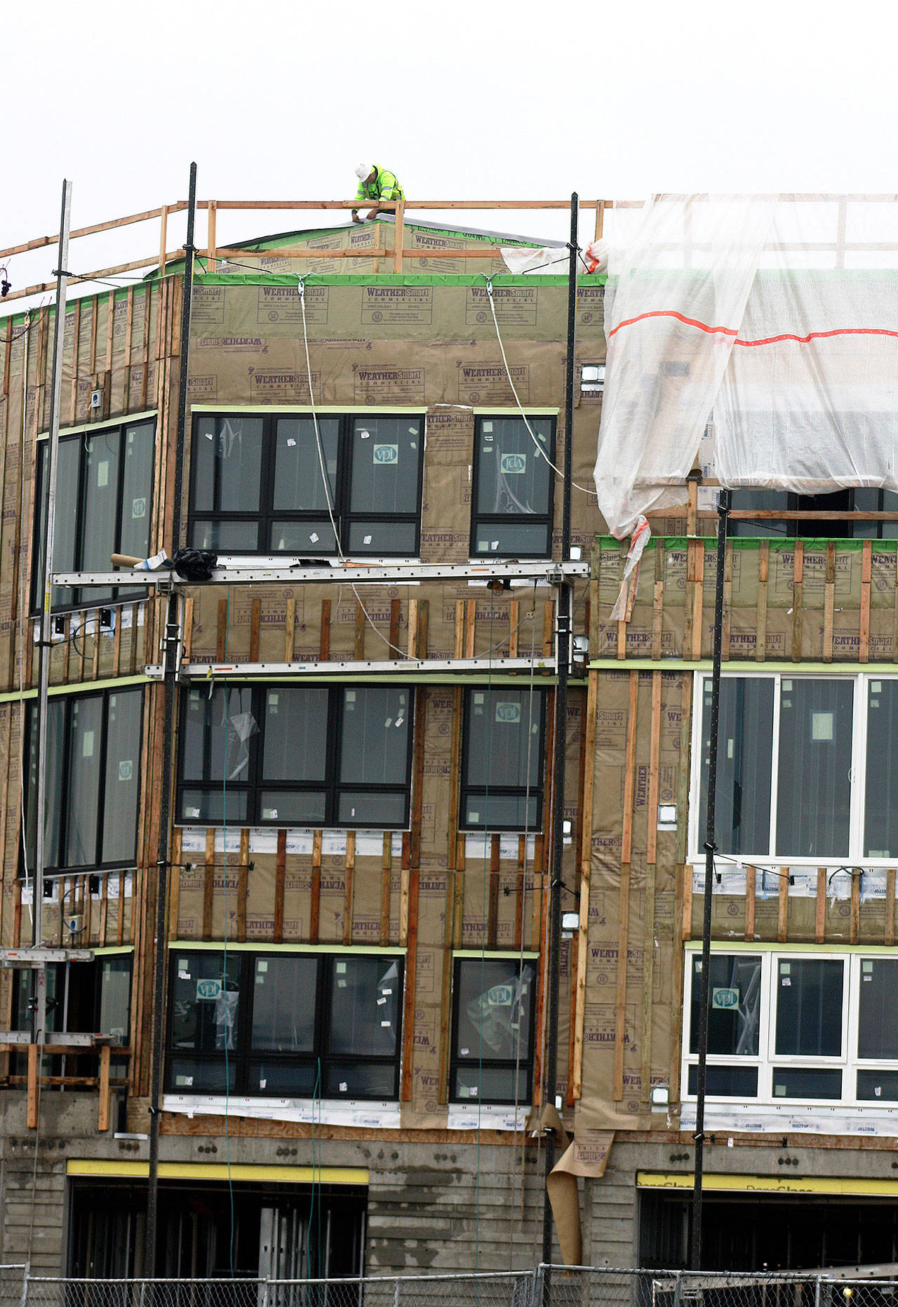 A construction worker stands atop the fourth floor of the new apartments going up along West Meeker Street, just west of 64th Avenue South, on Dec. 27 in Kent. The 308 units will be in three, four-story buildings. STEVE HUNTER, Kent Reporter