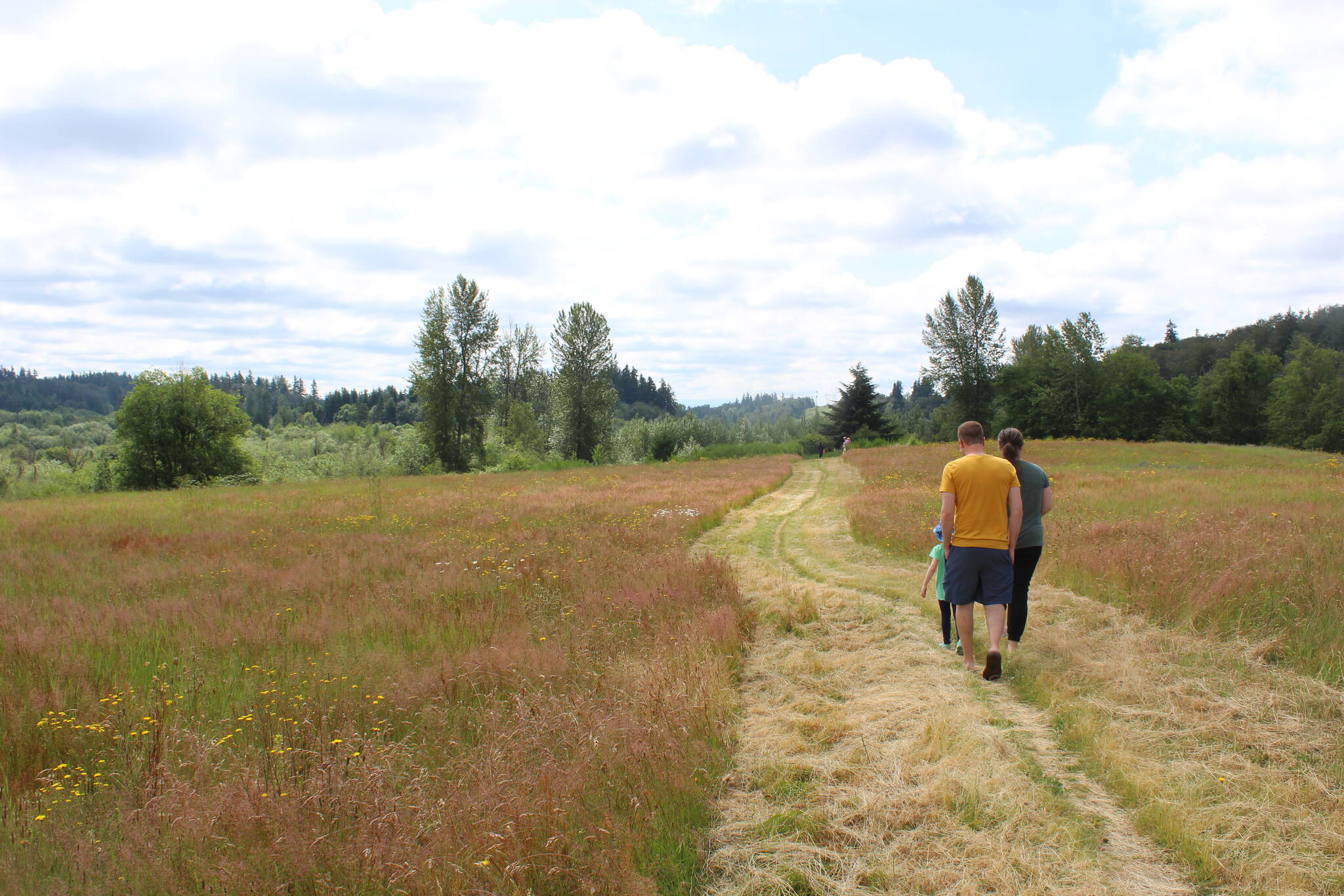 Residents walk the grounds of the future East Hill North Community Park. Photo by Bailey Jo Josie/Sound Publishing.