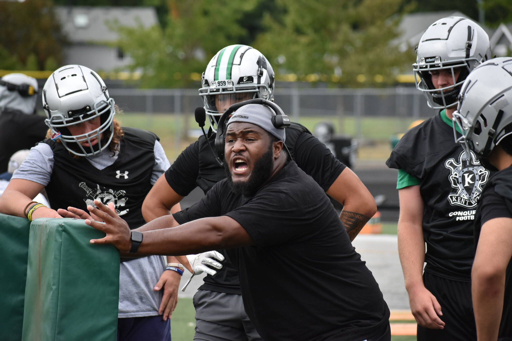 Kentwood assistant coach works with defensive linemen during practice.