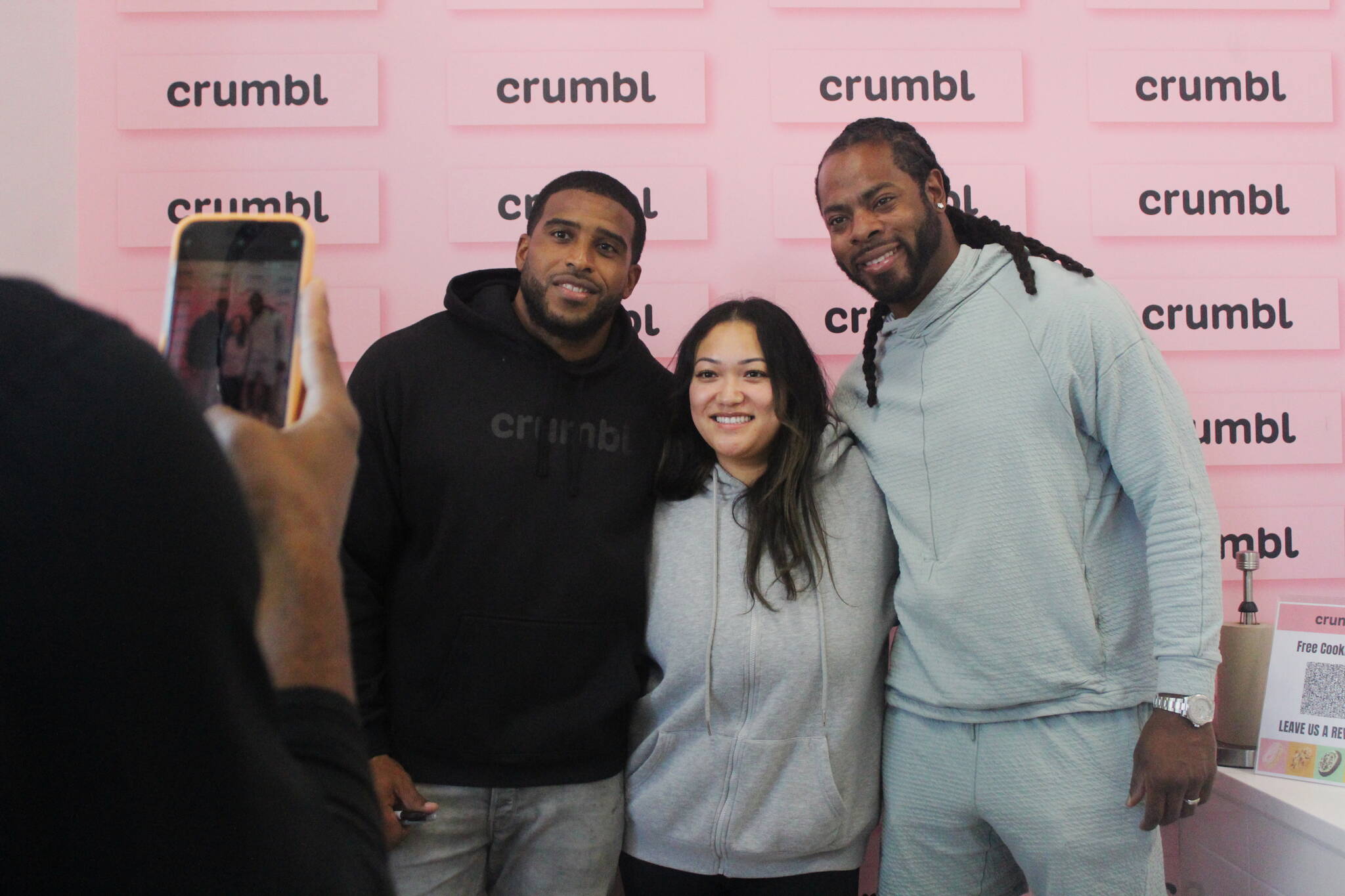 Bobby Wagner and Richard Sherman pose for a photo with a fan on the opening day of Crumbl Cookies, which Wagner co-owns. Photo by Bailey Jo Josie/Sound Publishing.